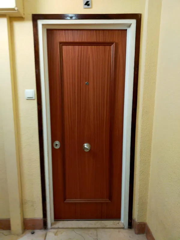 Puerta de seguridad en acabado sapeli instalada en un rellano