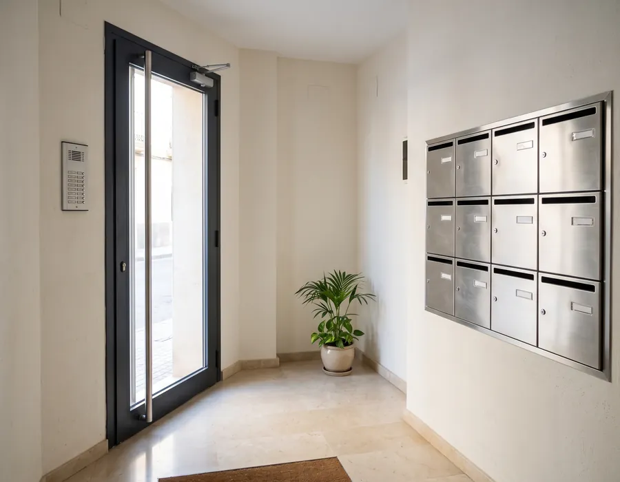 Portal de una comunidad de vecinos con la puerta de entrada, el portero automático y los buzones